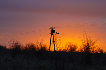 Silhouette of a power line on a background of sunrise.