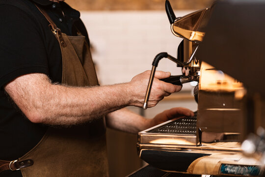 Mature male barista preparing espresso using coffee machine