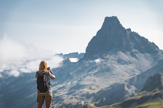 Young hiker Woman taking a picture with her cellphone in the top of a mountain. Discovery Travel Destination Concept.