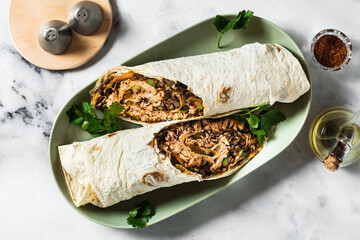 burrito with fried salmon and vegetables on a marble table. Mexican cuisine