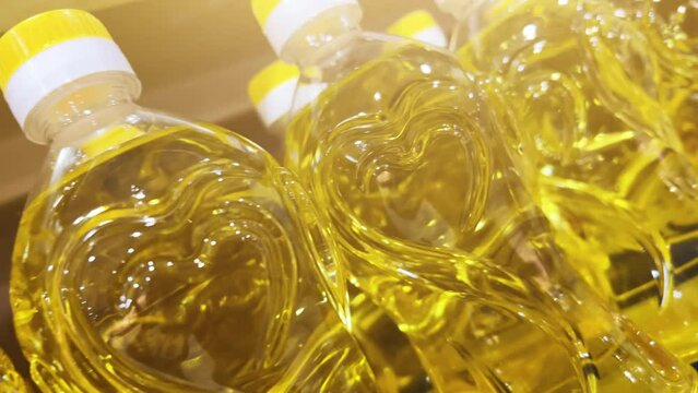 Sunflower or corn oil in plastic bottles line up on the shelf in a supermarket or a warehouse. Closeup shot. Dutch angle