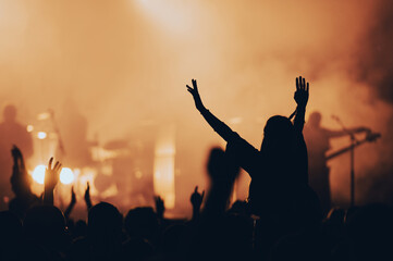 Silhouette of a woman with raised hands on a concert