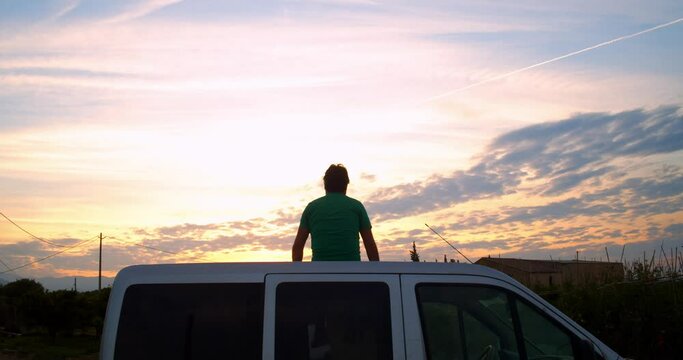 Man sitting in his caper van during a sunset. Travel and adventure concept