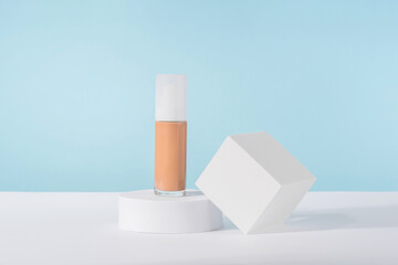 Cosmetic liquid foundation nude cream bottle mockup on white square block podium pedestal. Beige...