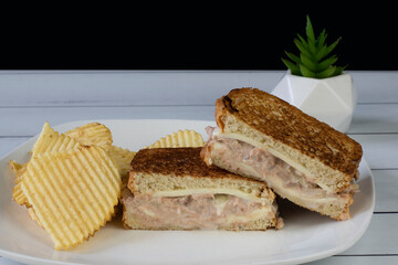 stacked tuna melt with a side  of potato chips,