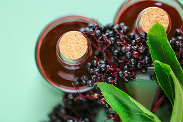 Elderberry syrup.Sambucus syrup.Red elderberry syrup in bottles set and ripe black elderberries on green background.Useful drink. Alternative medicine and homeopathy.Elderberry harvest 