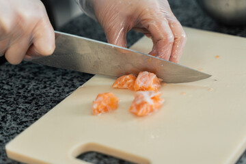chef cuts salmon with a knife in the kitchen