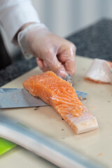 girl cleans salmon in gloves