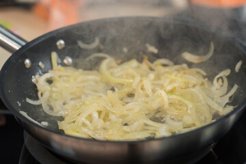 onions are fried in a frying pan in the kitchen