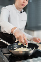 girl pouring onions into a frying pan