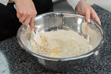 the cook is kneading the dough. flour and egg