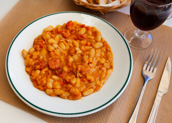 Appetizing braised beans with chorizo sausage pieces closeup