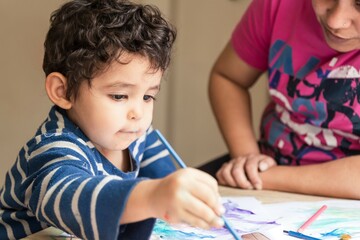 boy painting with his mom with brushes and paint
