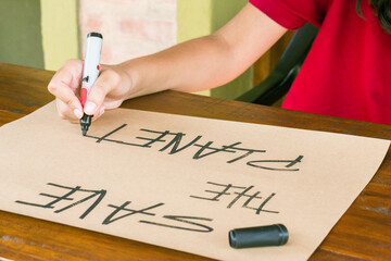Young Latina writes with a black marker on cardboard of ecological paper ``Save the planet??