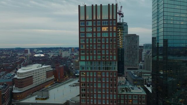 Elevated view of downtown buildings at dusk. Fly around modern tall skyscrapers with glossy glass facades. Boston, USA