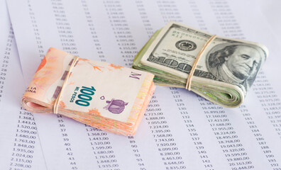 Folded hundred dollar bills and thousand Argentine pesos on exchange table