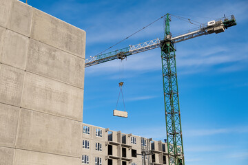 Construction crane on the background of an unfinished residential building. Housing construction,...