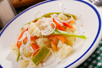 Fototapeta na wymiar Plate of tasty salad with cauliflower, onion, green beans and bell pepper