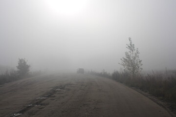 Obraz na płótnie Canvas road travel with a car in heavy fog with precipitation in clouds