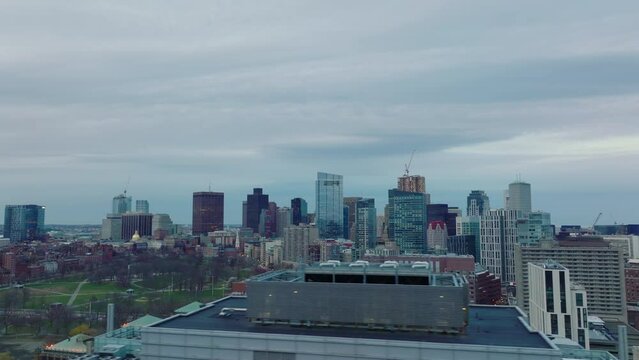 Aerial panoramic view of modern tall buildings in city centre at dusk. Sliding reveal of public park. Boston, USA