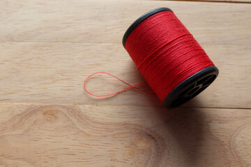 Red thread spool with copy space isolated on wooden background closeup.