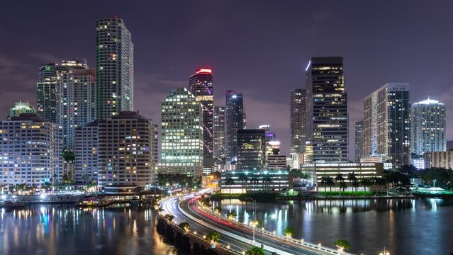 Night time lapse of traffic going over a bridge and the tall buildings of Miami Florida