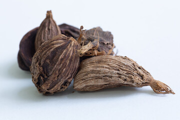 A top down image of black cardamom a spice commonly used in many traditional Indian dishes and cuisines, isolated on a white background