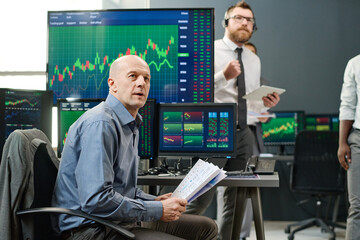 Obraz premium Group of professional investment specialist waiting for current stock trading finish looking at monitor in office