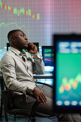 Busy young African American man wearing elegant clothes working in modern brokerage company...