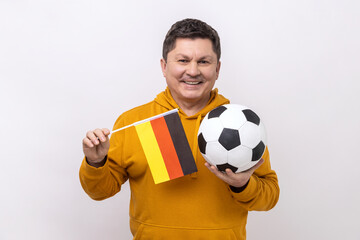 Middle aged man with toothy smile holding flag of germany and soccer black and white classic ball...