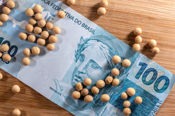 Soybeans spread over one hundred reais of brazilian money, conceptualizing agribusiness and the commodity market. in Brazil - obrazy, fototapety, plakaty