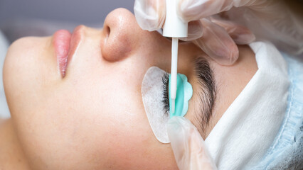 Young woman undergoing eyelash tinting and lamination procedure.