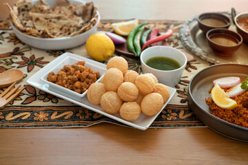 Indian cuisine, panipuri is snack from India, curry butter chicken, chicken tikka, biryani, and naan bread on wooden table, view from above