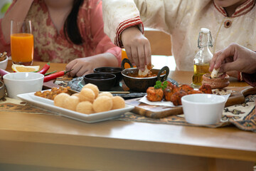 Indian cuisine, panipuri is snack from India, curry butter chicken, chicken Tikka, biryani, and naan bread on wooden table, boy and girl eating Indian food, using hand