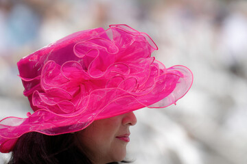 An attendee at a horse race, wearing a fancy hat.