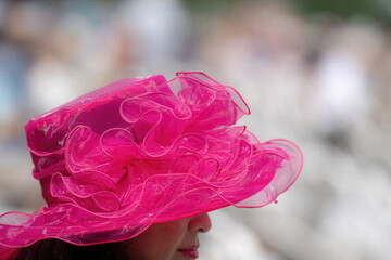 An attendee at a horse race, wearing a fancy hat.