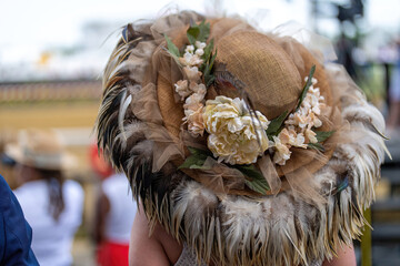 An attendee at a horse race, wearing a fancy hat.