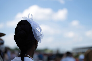 An attendee at a horse race, wearing a fancy hat.