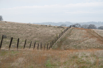 old wood post cattle fence over rolling hills