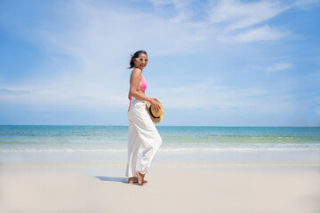 A young Asian girl in pink bikini spends vacation on the beach at Koh Samed Thailand.