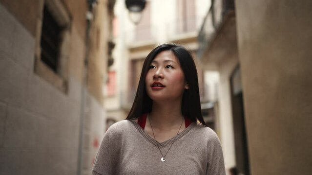 Beautiful Asian woman looking inspired walking down the narrow street alone. Pretty Japanese girl exploring new places