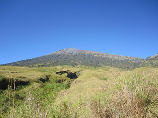 Obraz premium Mount Rinjani, the second highest volcano mountain in Indonesia, located in Lombok Island. A mountain with a beautiful crater lake called Segara Anak during a sunny day with blue sky.