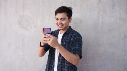 Fototapeta premium Happy young asian man watching news on mobile