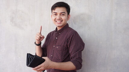 Happy young asian man holding wallet with hand expression