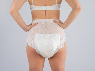 Rear view of a Woman in adult diapers on a white background. Incontinence problem.  - obrazy, fototapety, plakaty