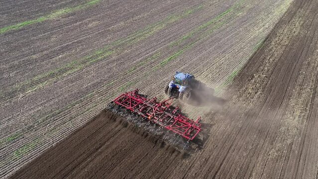 Agricultural tractor in the field fluff the earth. Aerial view 4k video