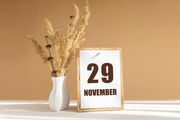 november 29. 29th day of month, calendar date.White vase with dried flowers on desktop in rays of...