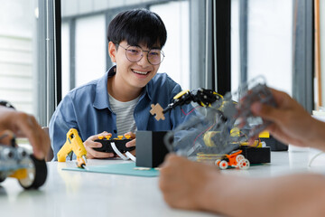 Asian teenager constructing robot arm project in science classroom. technology of robotics programing and STEM education concept.