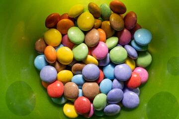 Fototapeta na wymiar Colorful chocolate beans in a green plastic plate