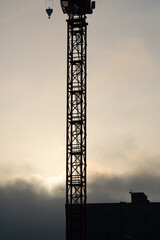 Construction crane in the evening with a cloudy sky in the background 